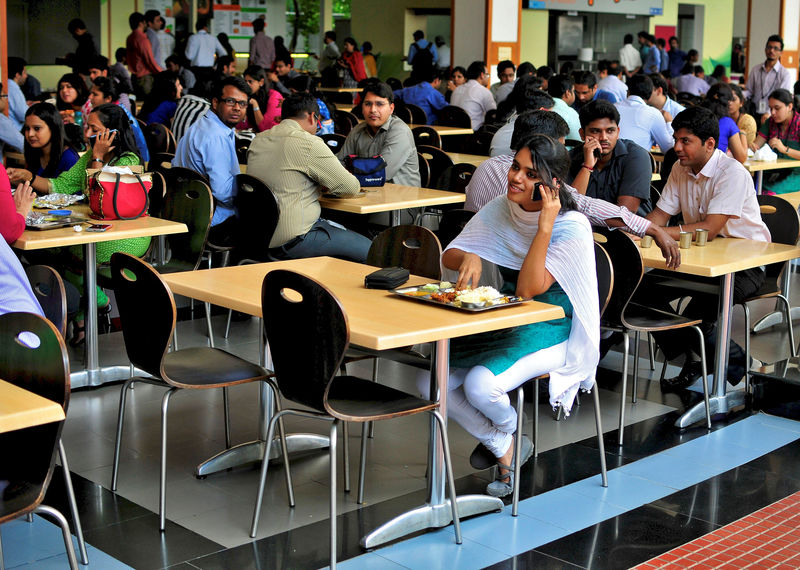 © Reuters. An employee speaks on a mobile phone as she eats her lunch at the cafeteria in the Infosys campus in Bengaluru