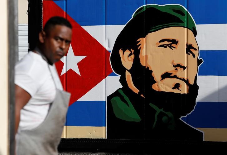 © Reuters. Homem visto em Havana em frente desenho de Fidel Castro junto a bandeira cubana