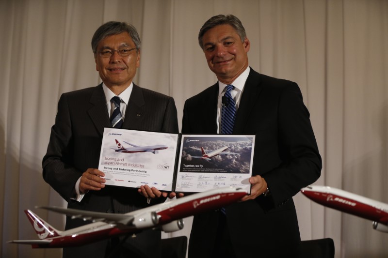 © Reuters. Conner, CEO of Boeing Commercial Airplanes, shows a document with Omiya, Chairman of the Board of Mitsubishi Heavy Industries Ltd. and Japan Aircraft Development Corporation Chairman, in Tokyo