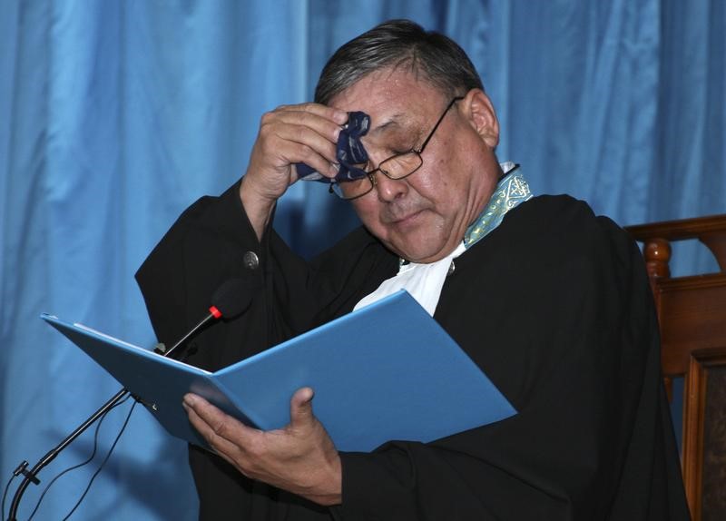 © Reuters. Judge Aralbai Nagashybayev wipes sweat as he tries a case of the defendants, accused of participating in December 2011 clashes in the oil town of Zhanaozen, during a court session in the Caspian port city of Aktau