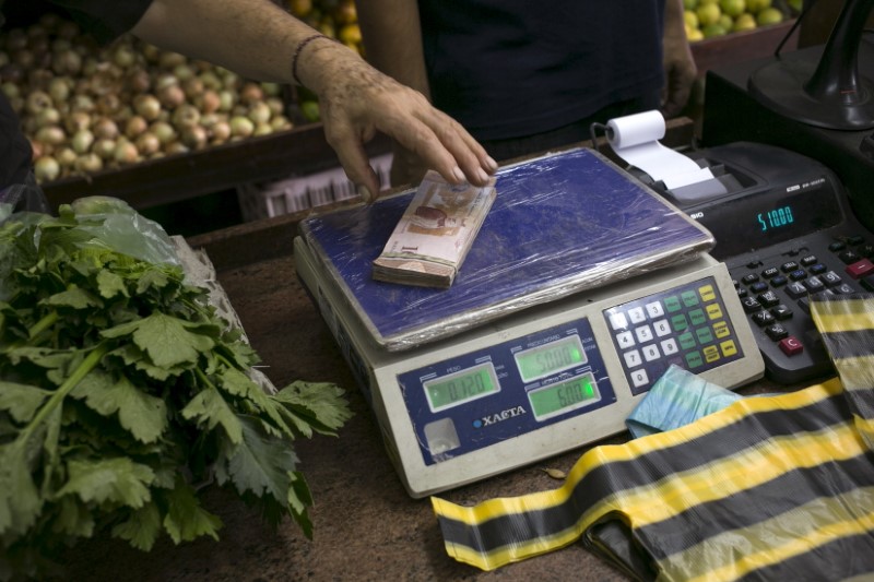 © Reuters. A clerk grabs a stack of Venezuelan 10 bolivars banknotes at a fruit and vegetable store in Caracas