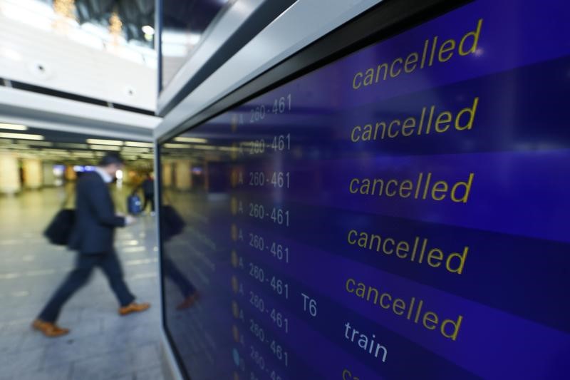 © Reuters. A passenger walks past a flight information board showing cancelled flights during a pilots strike of German airline Lufthansa at  Frankfurt airpor