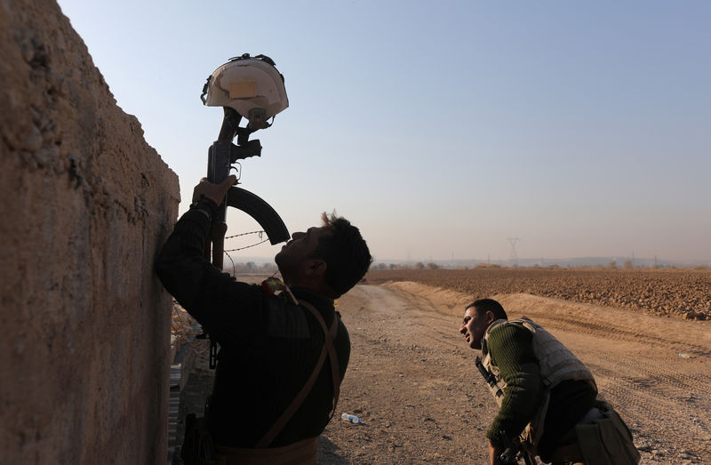 © Reuters. An Iraqi soldier uses his rifle to hold up a helmet as a decoy during clashes with Islamic State fighters in Al-Qasar, South-East of Mosul