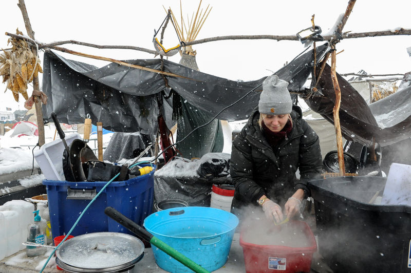 © Reuters. A woman washes dishes in the Oceti Sakowin camp in a snow storm during a protest against plans to pass the Dakota Access pipeline near the Standing Rock Indian Reservation, near Cannon Ball, North Dakota, U.S.