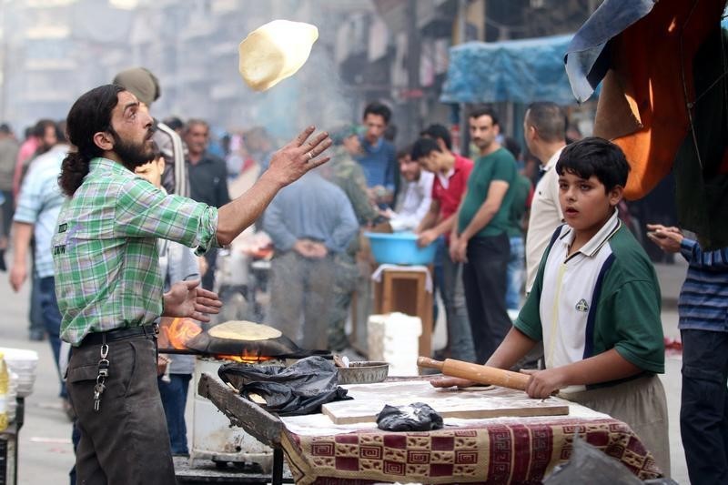 © Reuters. Мужчина готовит хлеб в контролируемом повстанцами районе Алеппо