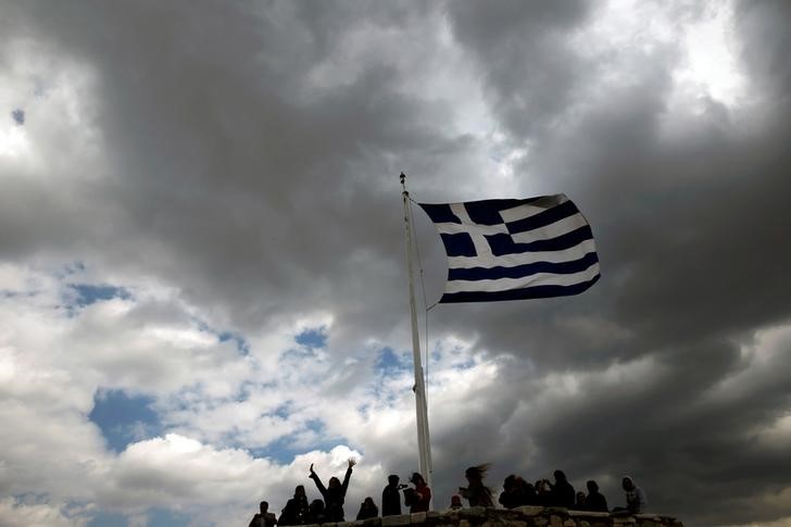 © Reuters. People are silhouetted under a fluttering Greek national flag atop the archaeological site of the Athens Acropolis