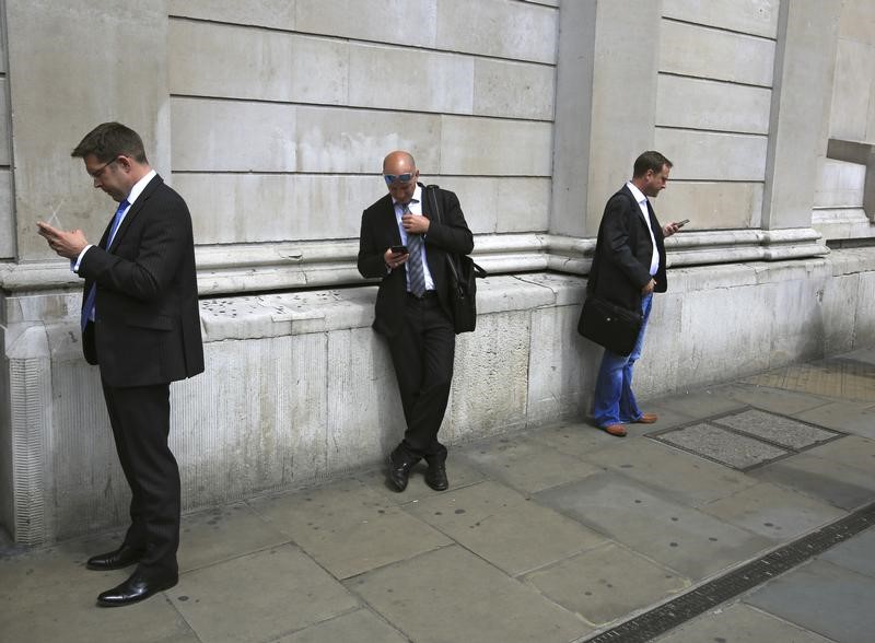 © Reuters. People use their mobile phones outside the Bank of England in the City of London