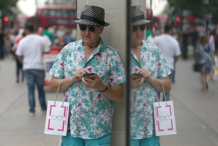 © Reuters. A shopper is reflected in the window of a store in London