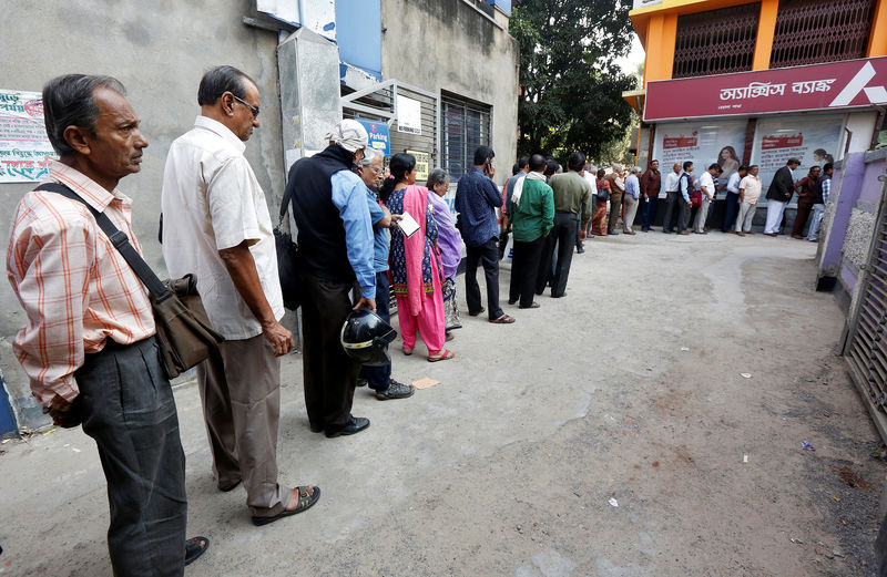 © Reuters. People queue outside a bank to withdraw cash and deposit their old high denomination banknotes in Kolkata