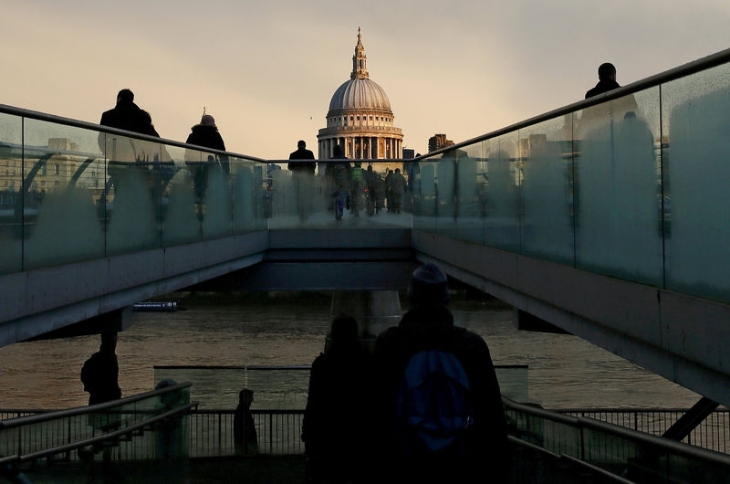 © Reuters. City workers walking towards St Paul's Cathedral as they cross the Millennium footbridge during sunrise in central London