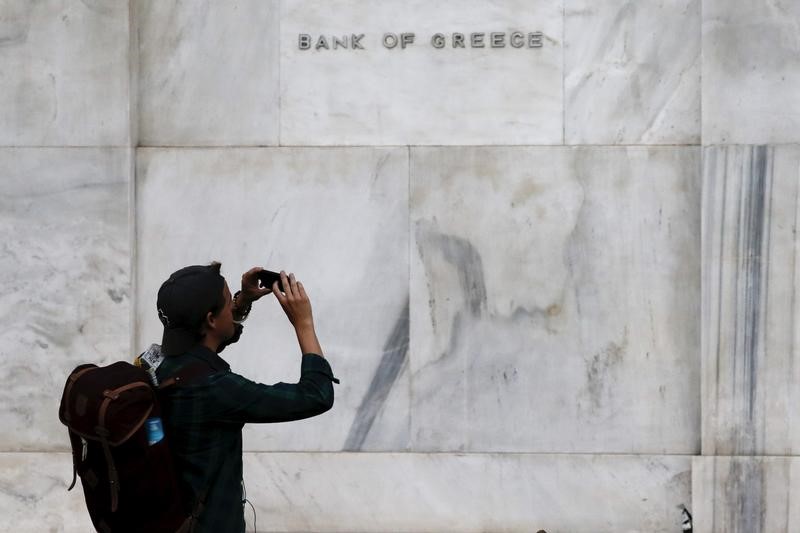 © Reuters. A man takes pictures with his mobile phone next to the Bank of Greece building in Athens