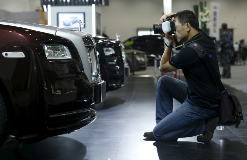 © Reuters. A man takes pictures of a Rolls-Royce Wraith car at the Imported Auto Expo in Beijing