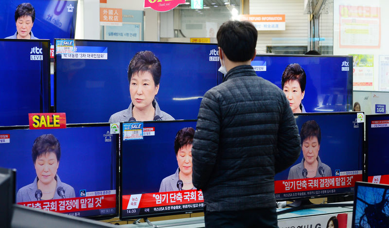 © Reuters. A man watches television broadcast of a news report on President Park Geun-hye releasing a statement to the public in Seoul