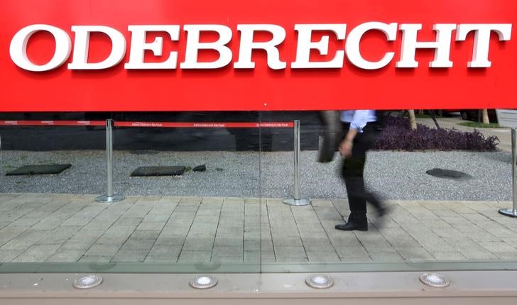 © Reuters. Homem caminha atrás de placa da Odebrecht na sede da empresa em São Paulo