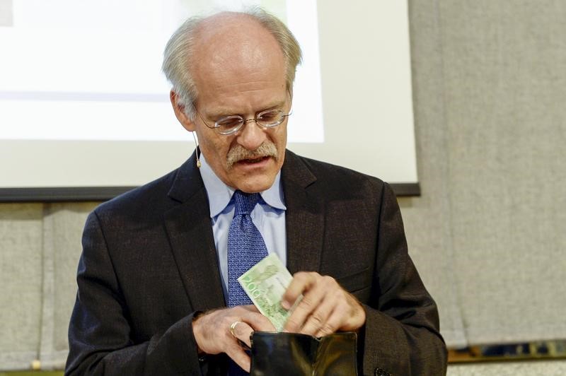 © Reuters. Stefan Ingves, the head of Sweden's central bank, the Riksbank, pulls a new 200 kronor bank note from his wallet at a news conference in Stockholm
