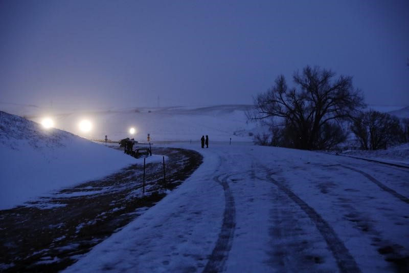 © Reuters. A couple stands lit by police lights near Backwater Bridge just outside of the Oceti Sakowin camp during ongoing demonstrations against the Dakota Access pipeline near the Standing Rock Indian Reservation, near Cannon Ball, North Dakota