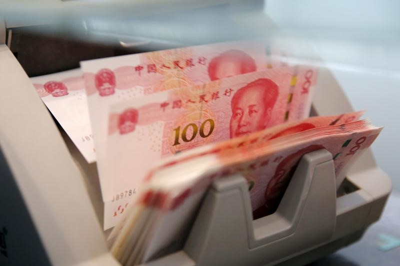 © Reuters. File picture of Chinese 100 yuan banknotes  in a counting machine while a clerk counts them at a branch of a commercial bank in Beijing