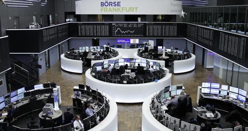 © Reuters. Traders work at their desks in front of the German share price index DAX board in Frankfurt