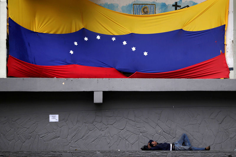 © Reuters. Homem deitado embaixo de bandeira da Venezuela em Caracas