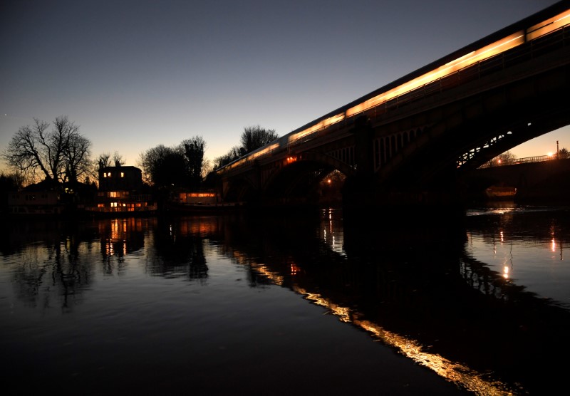 © Reuters. A passenger train is seen reflected as it crosses the River Thames at dusk in Richmond in west London, Britain
