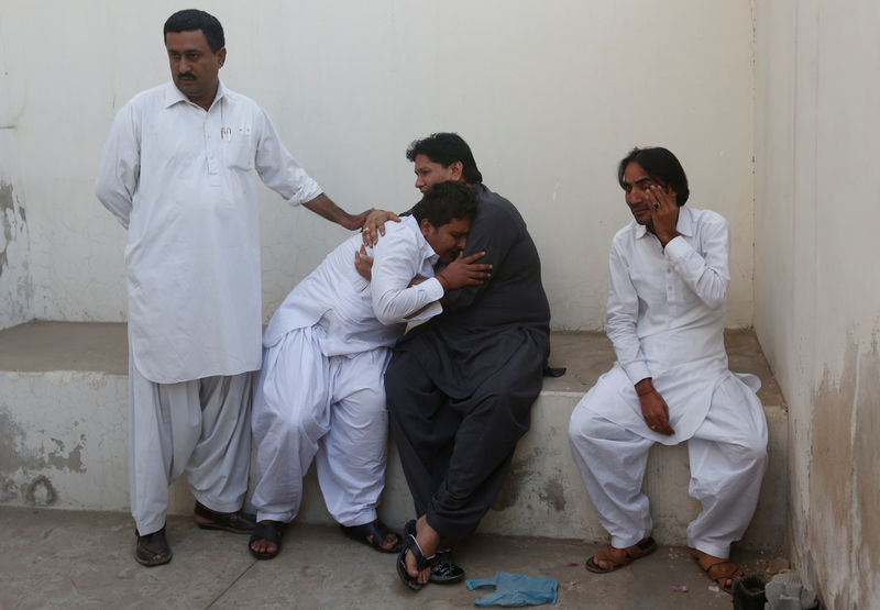 © Reuters. Men mourn the death of their relatives at a morgue after a fire erupted at a hotel early morning in Karachi