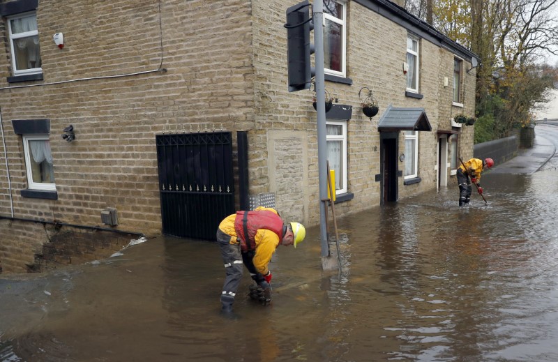 © Reuters. Emergency services workers try to clear flood water in Stalybridge