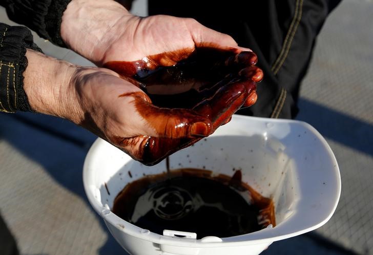 © Reuters. Рабочий демонстрирует образец нефти на месторождении Приобское, принадлежащем Роснефти