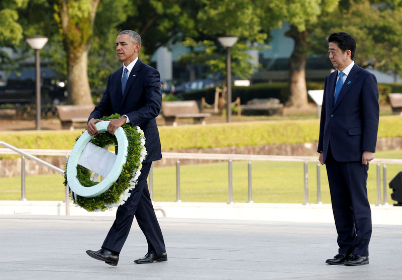 © Reuters. U.S. President Obama carries a wreath as Japanese PM Abe looks on, in front of a cenotaph at Hiroshima Peace Memorial Park in Hiroshima