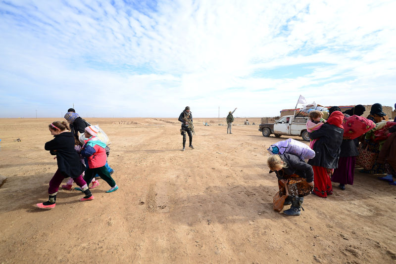 © Reuters. Displaced people, fleeing the violence of Islamic State militants in outskirts of Sinjar, walk past Shiite fighters in Sinjar