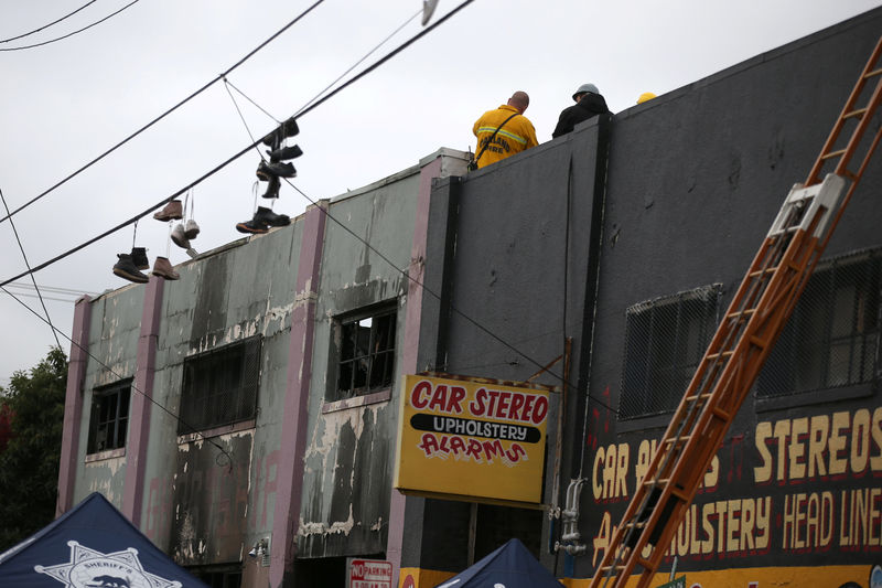 © Reuters. Firefighters work inside the burned warehouse following the fatal fire in the Fruitvale district of Oakland