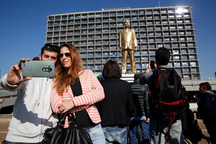 © Reuters. Pessoas tiram fotos em frente estátua dourada do primeiro-ministro de Israel, Benjamin Netanyahu, montada em uma praça de Tel Aviv