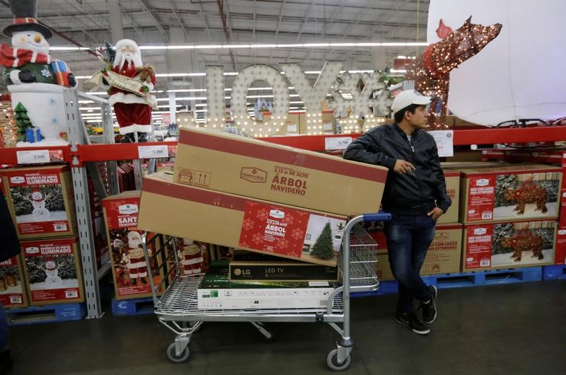 © Reuters. A shopper waits next to his cart with television screens and other items during a shopping season, 