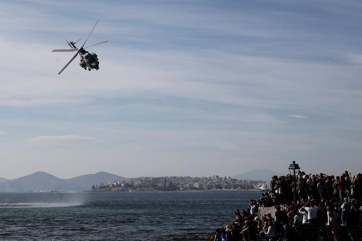 © Reuters. Spectators watch a Super Puma helicopter operating in a mock Search and Rescue operation, during a show marking the Hellenic Air Force's Patron Saint celebration, on the southern suburb of Faliro, in Athens