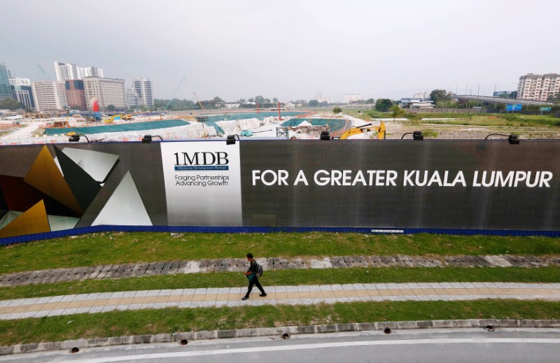 © Reuters. A man walks past a 1 Malaysia Development Berhad (1MDB) billboard at the funds flagship Tun Razak Exchange development in Kuala Lumpur