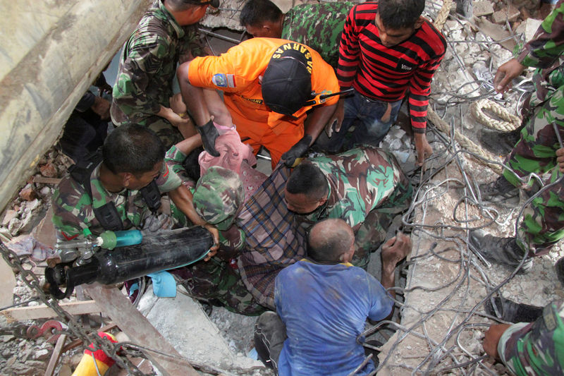 © Reuters. Membros de equipes de resgate ajudam sobrevivente após terremoto na província de Aceh, Indonésia