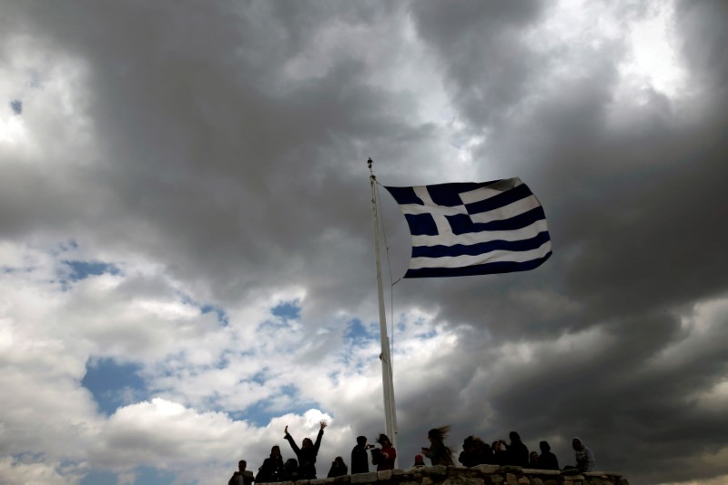 © Reuters. People are silhouetted under a fluttering Greek national flag atop the archaeological site of the Athens Acropolis