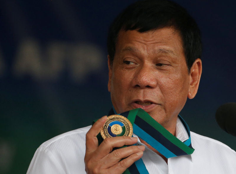 © Reuters. Philippine Pesident Rodrigo Duterte holds an emblem of the Armed forces as he speaks at the change of command for the new Armed Forces chief at a military camp  in Quezon city, Metro Manila