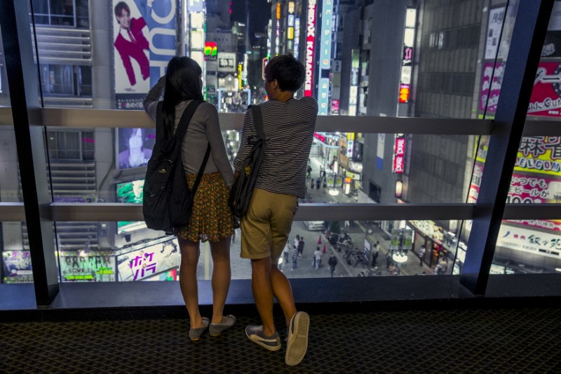 © Reuters. A couple overlooks Shinjuku's nightlife district of Kabukichoi in Tokyo