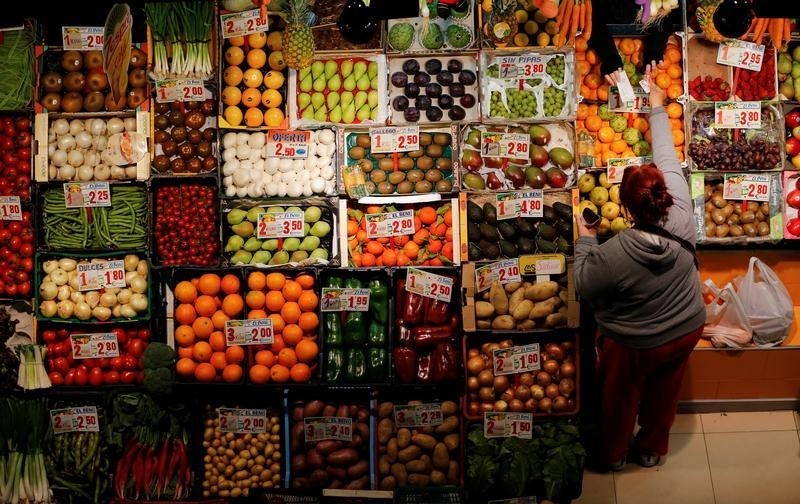 © Reuters. A woman makes purchases in a fruits and vegetables shop at a food market in the Andalusian capital of Seville