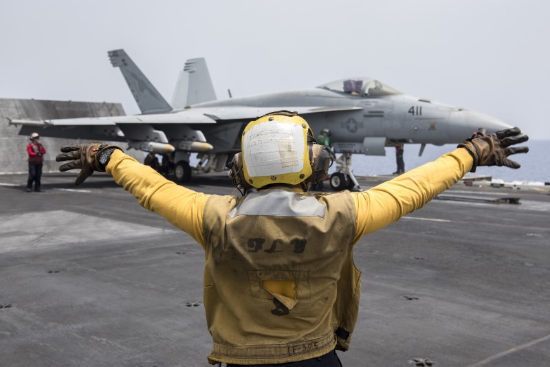 © Reuters. A U.S. Navy crewman directs an F/A-18E Super Hornet fighter jet on the flight deck of the aircraft carrier USS Harry S. Truman in the Mediterranean Sea