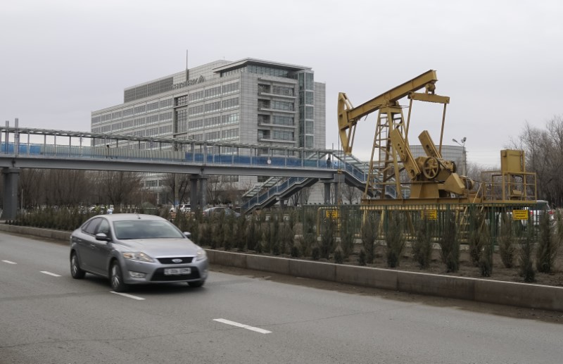 © Reuters. Car drives past oil well pump jack set as installation in front of Tengizchevroil LLP office in Atyrau