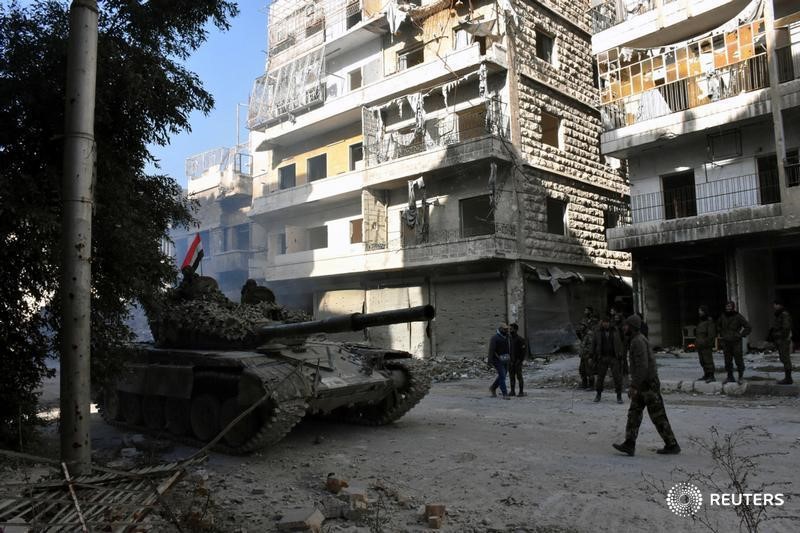 © Reuters. Forces loyal to Syria's President Bashar al-Assad stand near a tank in a government held area of Aleppo