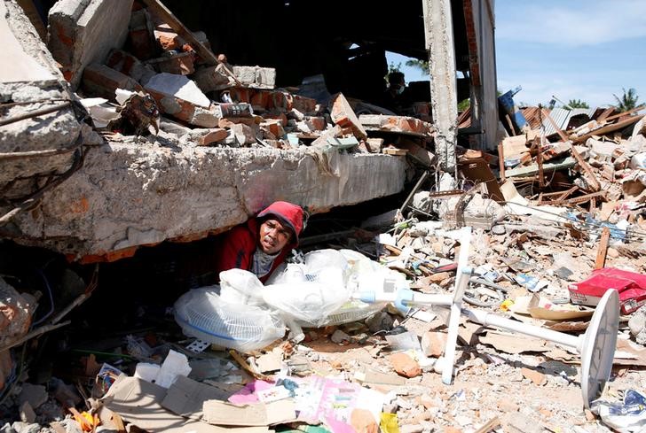 © Reuters. Homem em meio a destroços após terremoto em Pidie Jaya, Indonésia