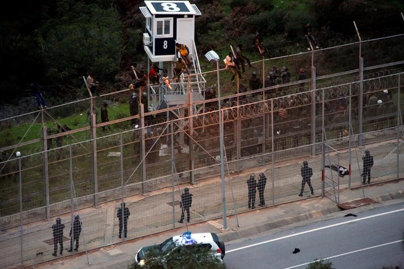 © Reuters. مهاجرون أفارقة يقتحمون السور الحدودي إلى جيب سبتة الأسباني