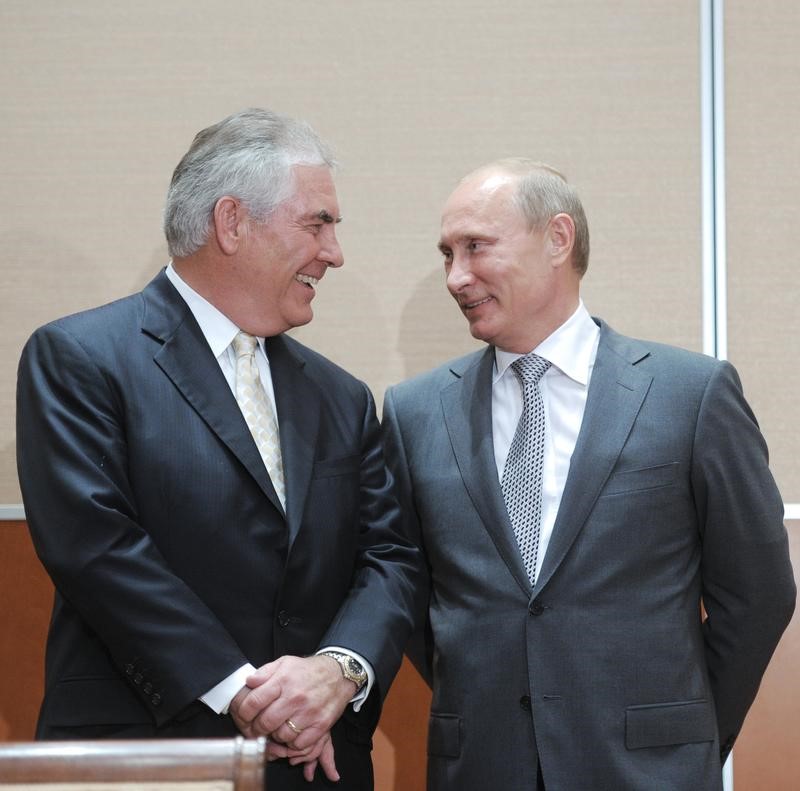 © Reuters. Russian Prime Minister Putin speaks with Exxon CEO Tillerson at a signing ceremony in the Black Sea resort of Sochi