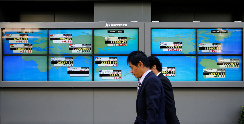 © Reuters. Men walk past an electronic board showing Japan's Nikkei average outside a brokerage in Tokyo