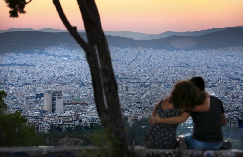 © Reuters. People watch the sun set from Lycabettus Hill in Athens