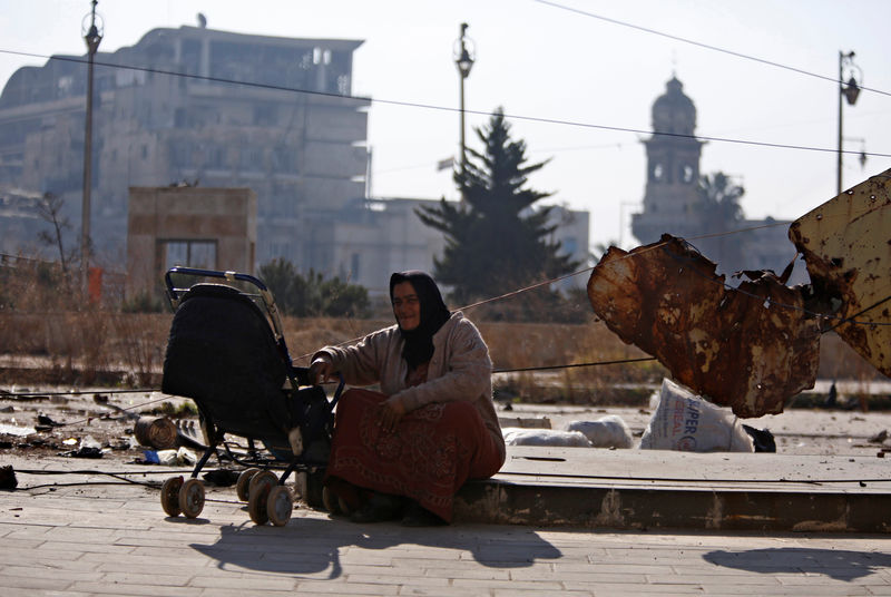 © Reuters. Mulher com bebê vista em praça na cidade síria de Aleppo