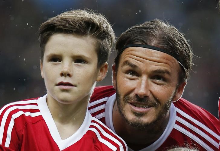 © Reuters. David Beckham e filho Cruz durante amistoso na Inglaterra