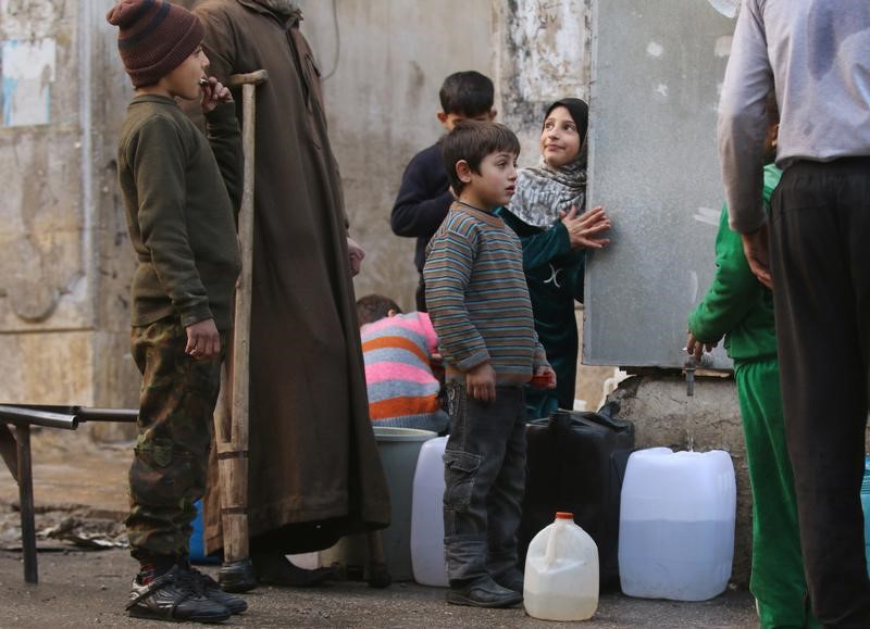 © Reuters. Crianças enchem galões d'água em área tomada por rebeldes na cidade síria de Aleppo